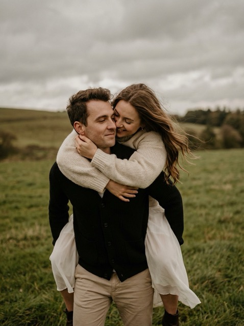 Romantic couple in a windy field, intimate and carefree.